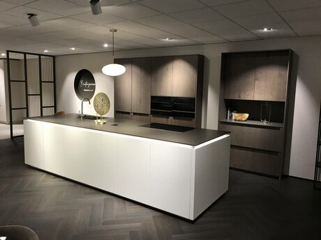 Showroomkeuken Deze sterk afgeprijsde showroomkeuken kun je vinden bij Brugman in Capelle ad IJssel. Het is een eiland-keuken in de kleur wit softmat / eiken barolol en in de stijl modern. Je profiteert nu van 64% korting, waardoor deze keuken al voor € 19975 van jou kan zijn! Heb je interesse in deze keuken of heb je nog vragen? Bel dan gerust naar <a href="tel:0102587555">0102587555</a> of mail naar <a href="mailto:capelleadijssel@brugman.nl">capelleadijssel@brugman.nl</a>. Je kunt ook vrijblijvend een bezichtiging plannen. Brugman keukens en badkamers Capelle